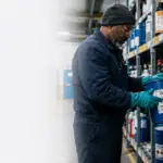 Worker handling labeled chemical containers under a hazard communication program in a manufacturing facility