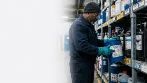 Worker handling labeled chemical containers under a hazard communication program in a manufacturing facility